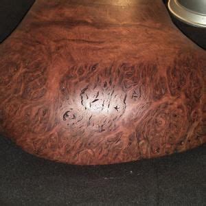 A Close Up Of A Wooden Table With Metal Bowl On It S Side And Black Surface