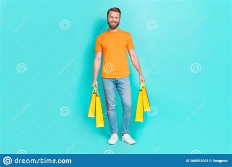 Full Body Photo Of Funky Beard Guy Hold Bags Wear T Shirt Jeans Boots Isolated On Teal Color