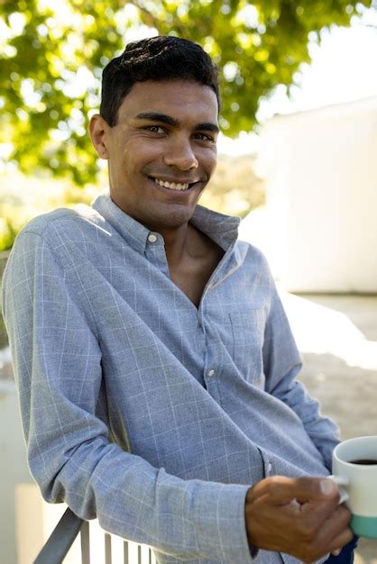 Premium Photo Portrait Of Happy Biracial Man Holding Mug On Balcony