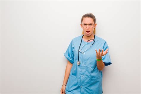 Joven enfermera latina que parece enojada molesta y frustrada gritando wtf o qué te pasa contra