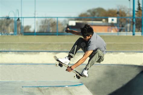 Jovem Patinador Segurando Seu Skate Enquanto Pulava No Ar Imagem De