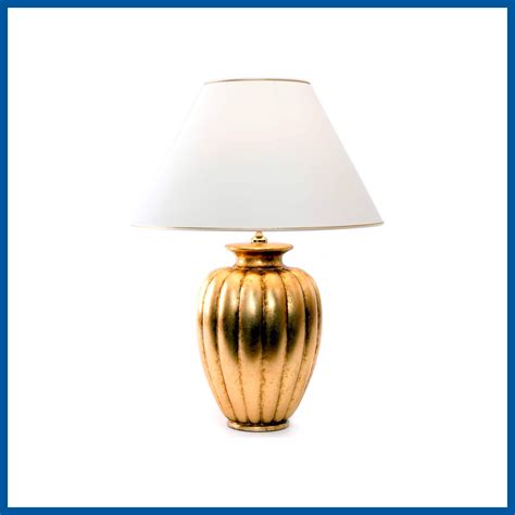 A Gold Lamp With A White Shade On It S Base And A Blue Frame Around The