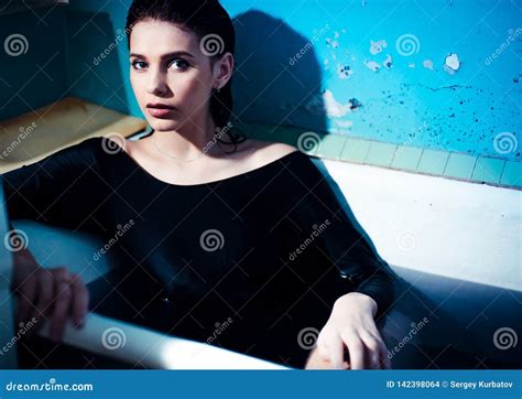 Girl With Bare Shoulders Lying In The Bathroom With Colored Purple Water Fashion Concept Stock