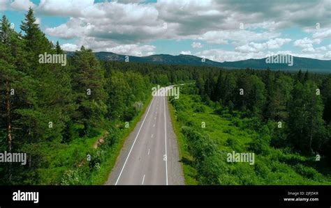 Aerial View Of Road Across The Forest On Blue Cloudy Sky Background