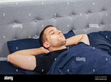 Top View Of A Handsome Young Man Sleeping Comfortably On The Bed At