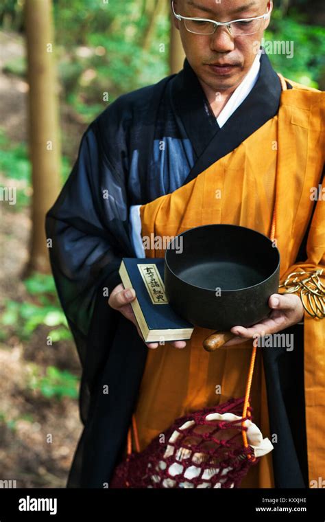 Buddhist Monk With Shaved Head Wearing Black And Yellow Robe Standing