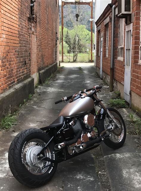 A Motorcycle Is Parked In An Alley Between Two Brick Buildings With