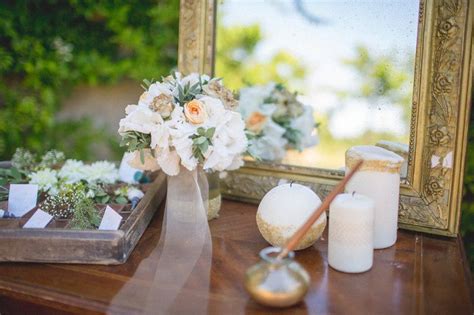 Flowers And Candles Sit On A Table In Front Of A Mirror With A Gold Frame