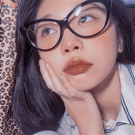 A Woman Wearing Glasses With Her Hand On Her Chin