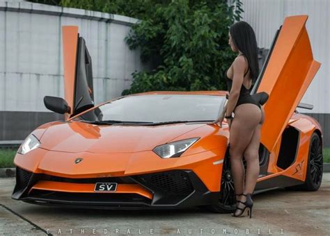 A Woman Standing Next To An Orange Sports Car