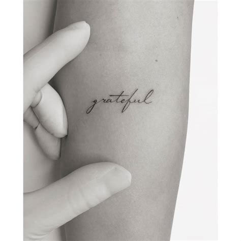 Tattoo of the word "grateful" located on the inner