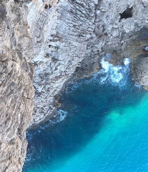 The Water Is Blue And Green In This Rocky Cliff Side Area With People