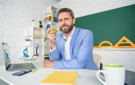 Profesor De Escuela Alegre En El Aula Almorzando Con Manzana Foto Premium