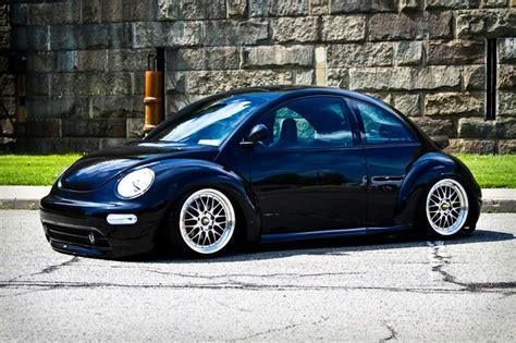 Black Volkswagen New Beetle Parked In Front Of Stone Wall