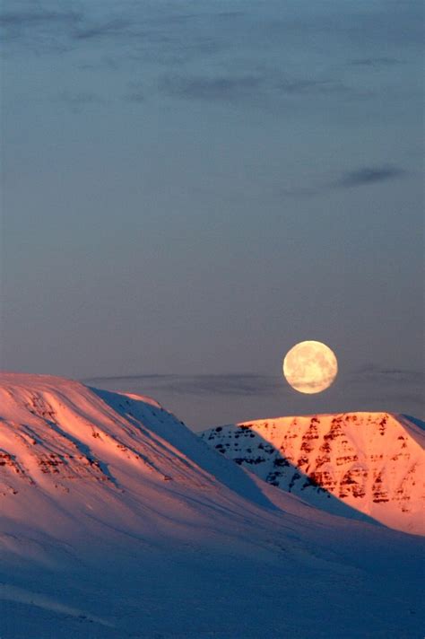 The Moon Is Setting On Top Of A Snowy Mountain