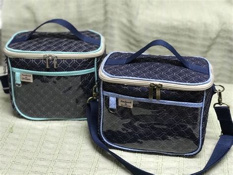 Two Blue And Black Lunch Bags Sitting On Top Of A White Bed Next To