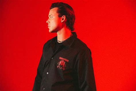 A Man Standing In Front Of A Red Background Wearing A Black Shirt With