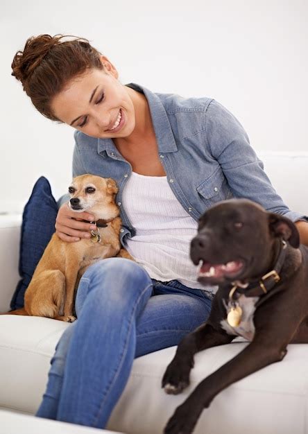 Sofá de mujer y sonrisa con perros para el cuidado del amor y la unión