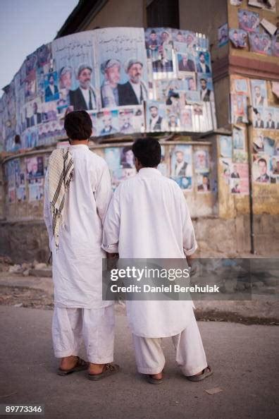 Afghan men hold hands as they look at posters showing candidates for ...