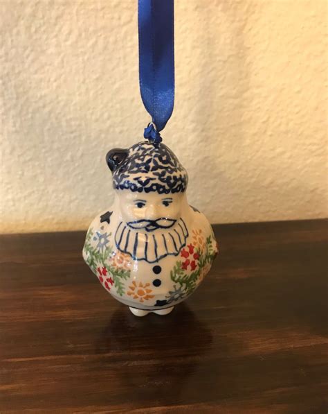 A Ceramic Ornament With A Blue Ribbon Hanging From Its End On A Wooden