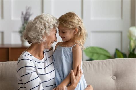 Smiling Grandmother Relax Cuddling With Small Granddaughter Stock Image