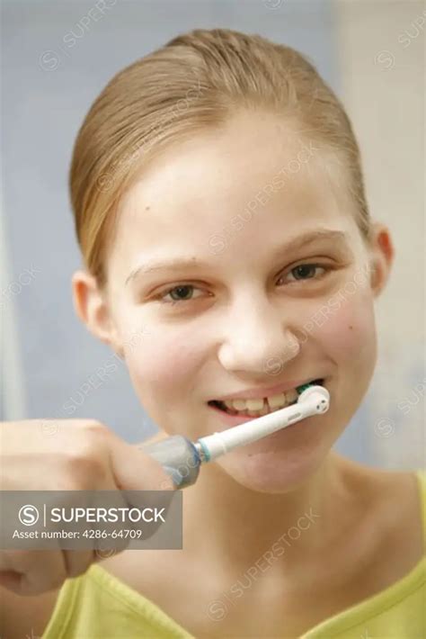 Girl Brushing Her Teeth With Electric Toothbrush Superstock