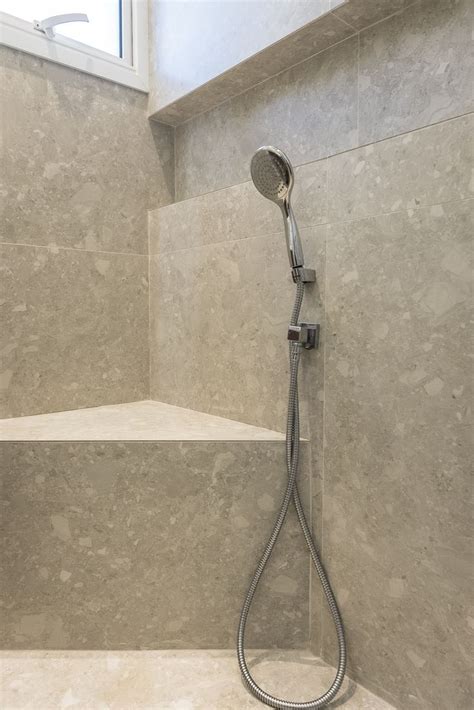 A Shower Head In The Corner Of A Bathroom With Marble Walls And