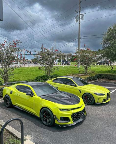 Two Yellow Sports Cars Parked Next To Each Other In A Parking Lot On A