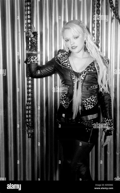 Pretty Blonde Girl Wearing Black Leather Jacket Against A Wall With