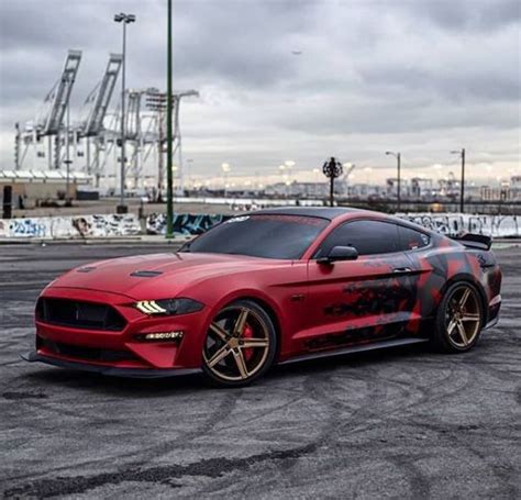 A Red Sports Car Parked In A Parking Lot With Other Cars Behind It And