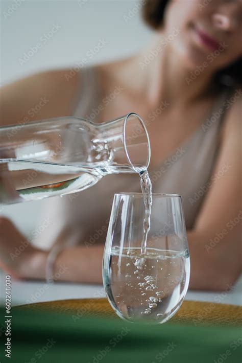 Young Woman Is Pouring Purified Fresh Drink Water From Bottle Into The