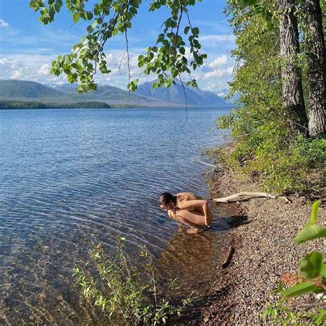 A Naked Woman Sitting On The Shore Of A Lake