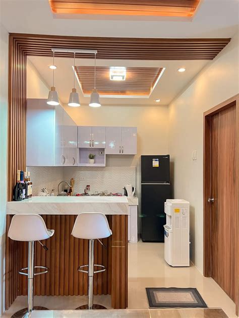 A Kitchen With Two Bar Stools Next To A Refrigerator