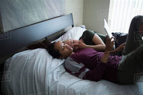 High Angle View Of Lesbian Couple Lying On Bed While Using Digital Tablet At Home Royalty Free
