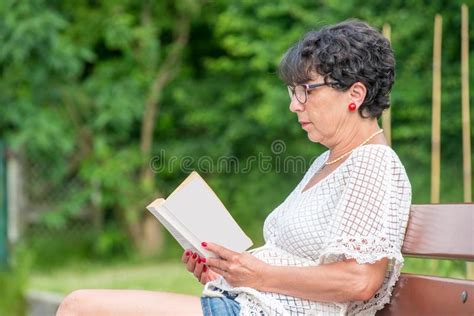 Livro De Leitura Superior Bonito Da Mulher No Jardim Imagem De Stock