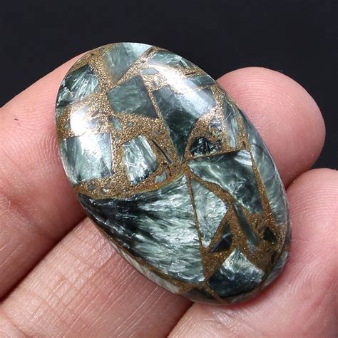 A Close Up Of A Person Holding A Rock In Their Hand With Gold Leaf