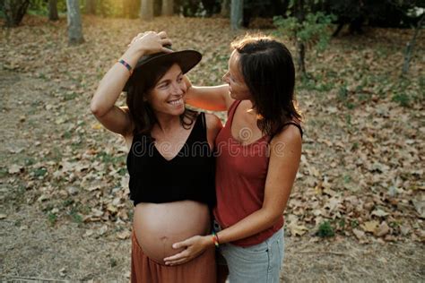 Closeup Of A Pregnant Lesbian Couple Doing A Photoshoot In A Park Stock