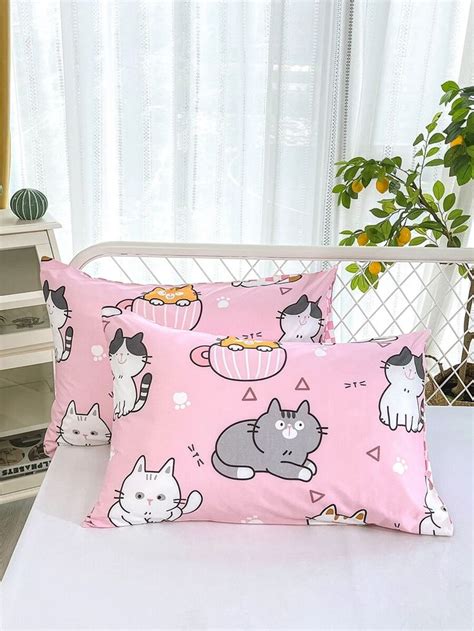 Two Pillow Cases With Cats On Them Sitting On A White Bed In Front Of A