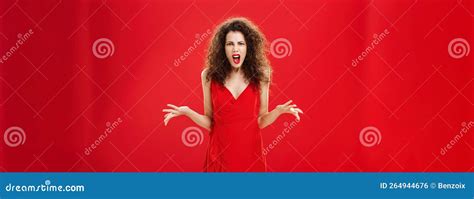 Dissatisfied Angry And Attractive Curly Haired Female In Stylish Red