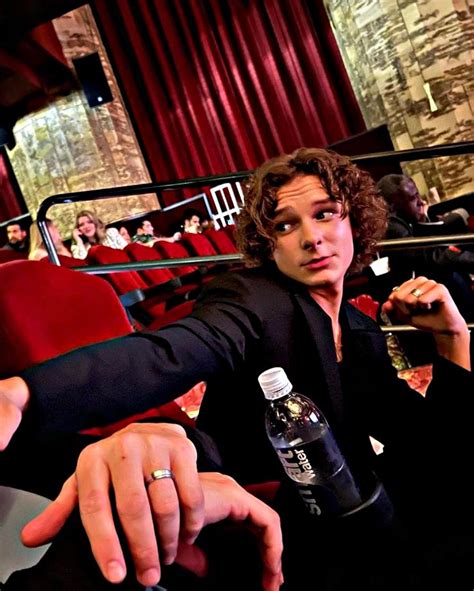 A Man Sitting In A Theater Holding Onto A Bottle