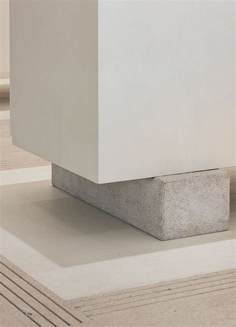 A Concrete Block Sitting On Top Of A Floor Next To A White Wall And Rug