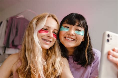 Two Multiracial Girls In Eye Patches Taking Selfie On Mobile Phone