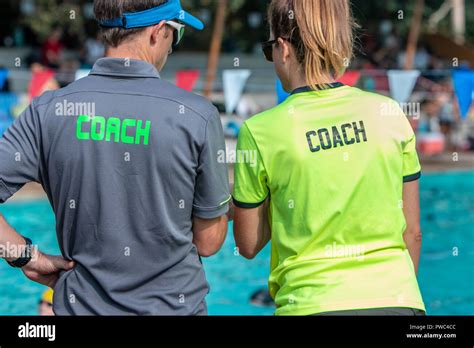 Back View Of Male And Female Swimming Coaches Wearing Coach Shirt