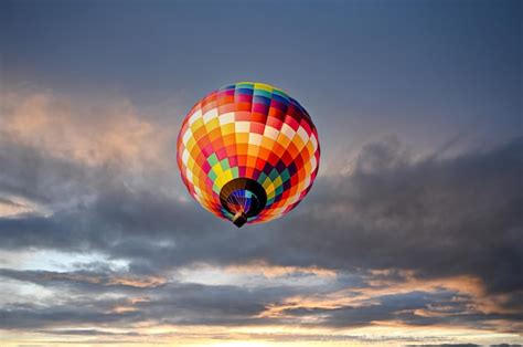 Balão de ar quente colorido voando sobre o céu ao pôr do sol Foto