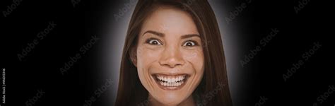 Scary face expression of crazy Asian girl with evil smile on black background banner. Woman ...