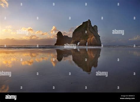 Archway Islands Reflected In Wet Sands Of Wharariki Beach At Sunset