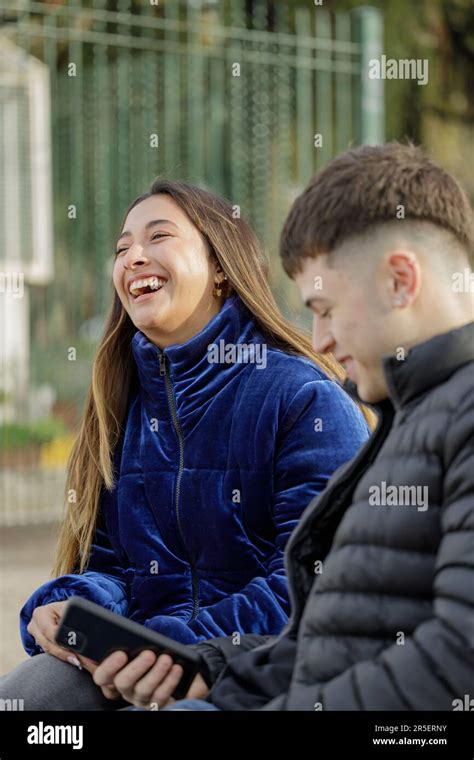 Latina Girl Laughing Sitting On A Plaza Bench With Her Boyfriend Stock Photo Alamy