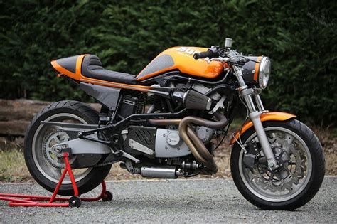 An Orange And Black Motorcycle Parked On Top Of A Gravel Road Next To