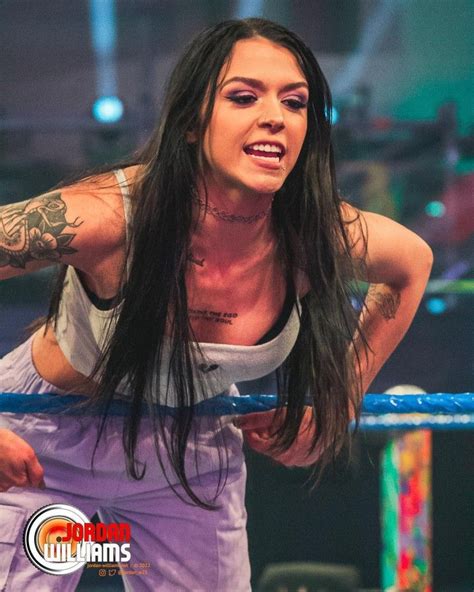 a woman with long hair standing in front of a wrestling ring holding a ...