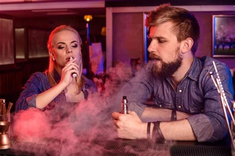 Um homem e uma mulher fumando cigarro eletrônico em um bar vape Foto